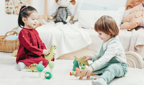 Two preschool children playing with wooden dinosaur toys